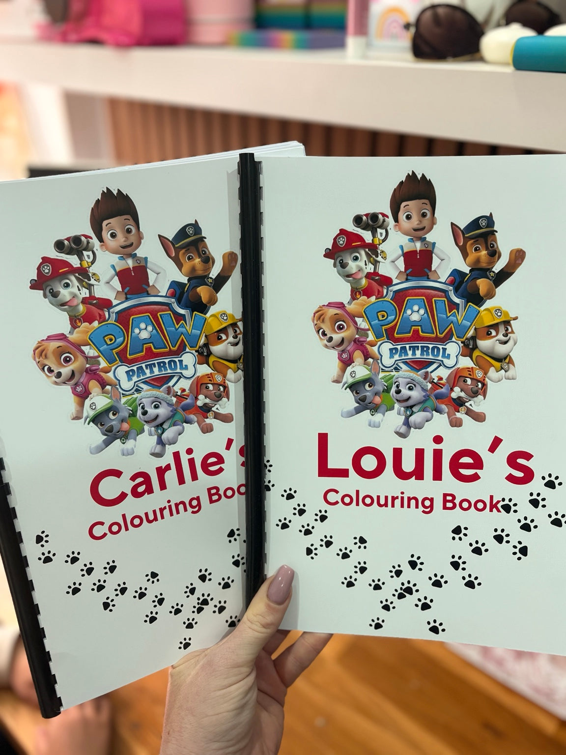 Two personalised children's colouring books with names on their comb-bound covers